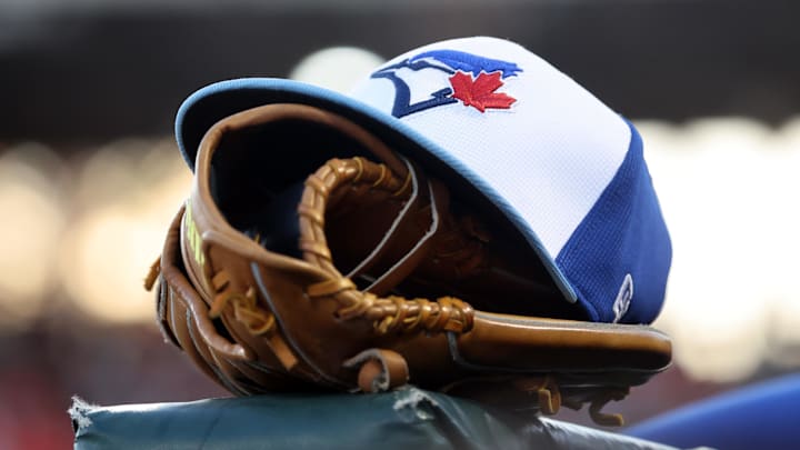 Mar 18, 2025; Sarasota, Florida, USA;  A detail view of a Toronto Blue Jays hat and glove against the Baltimore Orioles at Ed Smith Stadium. 