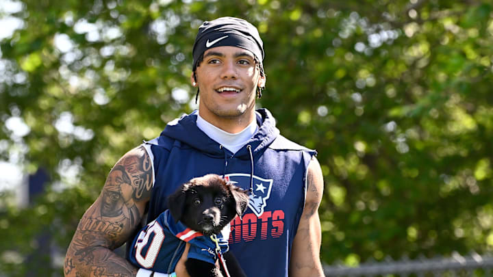 Jul 23, 2025; Foxborough, MA, USA; New England Patriots cornerback Christian Gonzalez (0) delivers a puppy to a local family as part of the Patriots pet adoption event before training camp at Gillette Stadium. Mandatory Credit: Eric Canha-Imagn Images