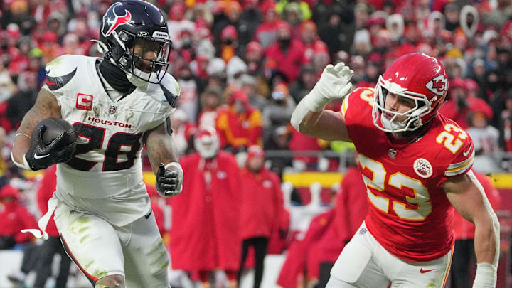 Jan 18, 2025; Kansas City, Missouri, USA; Houston Texans running back Joe Mixon (28) runs the ball as Kansas City Chiefs linebacker Drue Tranquill (23) defends during the second half of a 2025 AFC divisional round game at GEHA Field at Arrowhead Stadium.