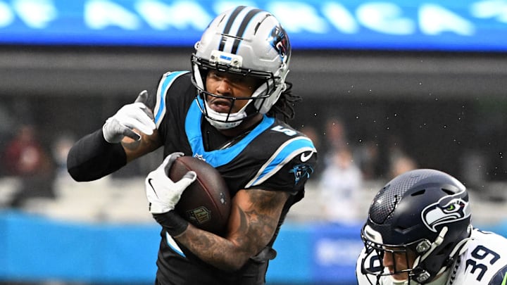 Dec 28, 2025; Charlotte, North Carolina, USA; Carolina Panthers running back Rico Dowdle (5) runs the ball against Seattle Seahawks safety Ty Okada (39) and linebacker Drake Thomas (42) (obscured) during the second quarter at Bank of America Stadium. Mandatory Credit: Bob Donnan-Imagn Images