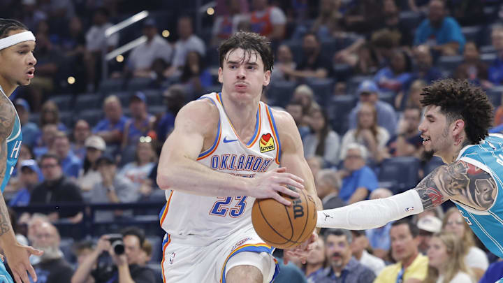 Oct 9, 2025; Oklahoma City, Oklahoma, USA; Oklahoma City Thunder guard Brooks Barnhizer (23) drives between Charlotte Hornets guard Tre Mann (23) and guard Lamelo Ball (1) during the second quarter of a game between the Charlotte Hornets and the Oklahoma City Thunder at Paycom Center. Mandatory Credit: Alonzo Adams-Imagn Images