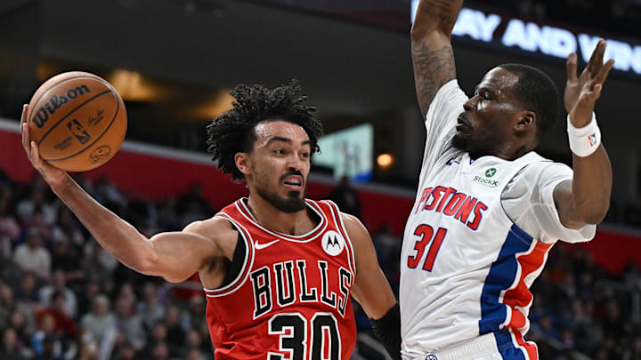 Jan 7, 2026; Detroit, Michigan, USA; Chicago Bulls guard Tre Jones (30) passes the ball past Detroit Pistons guard Javonte Green (31) under the basket in the fourth quarter at Little Caesars Arena. Mandatory Credit: Lon Horwedel-Imagn Images