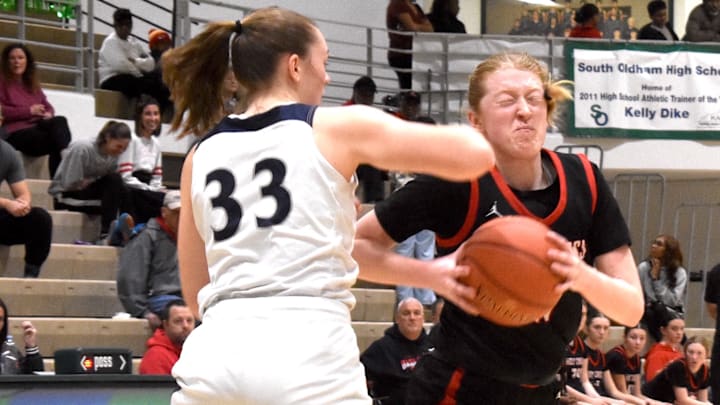 Holy Cross-Covington (No. 13) junior Riley Eberhard tries to avoid an inadvertent forearm from South Oldham freshman Hailey Hammer in a game Saturday, Feb. 14, 2026.