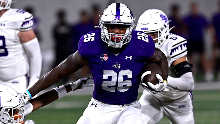 ACU running back Jordon Vaughn stiff-arms SFA cornerback Aaron Sears as he carries the ball downfield.