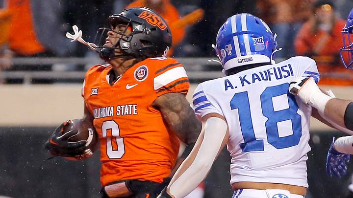 Oklahoma State's Ollie Gordon II (0) reacts after a score next BYU's Ace Kaufusi (18) in the second half of the college football game between the Oklahoma State University Cowboys and the Brigham Young Cougars at Boone Pickens Stadium in Stillwater, Okla., Saturday, Nov. 25, 2023.