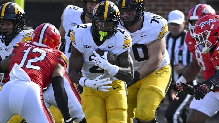 Nov 23, 2024; College Park, Maryland, USA;  Iowa Hawkeyes running back Kaleb Johnson (2) rushes as Maryland Terrapins defensive back Dante Trader Jr. (12) defends during the first half at SECU Stadium. Mandatory Credit: Tommy Gilligan-Imagn Images