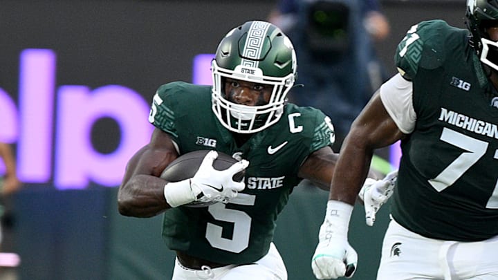Aug 30, 2024; East Lansing, Michigan, USA;  Michigan State Spartans running back Nate Carter (5) follows blocker Michigan State Spartans offensive lineman Kristian Phillips (71) during the game against the Florida Atlantic Owls at Spartan Stadium. Mandatory Credit: Dale Young-Imagn Images