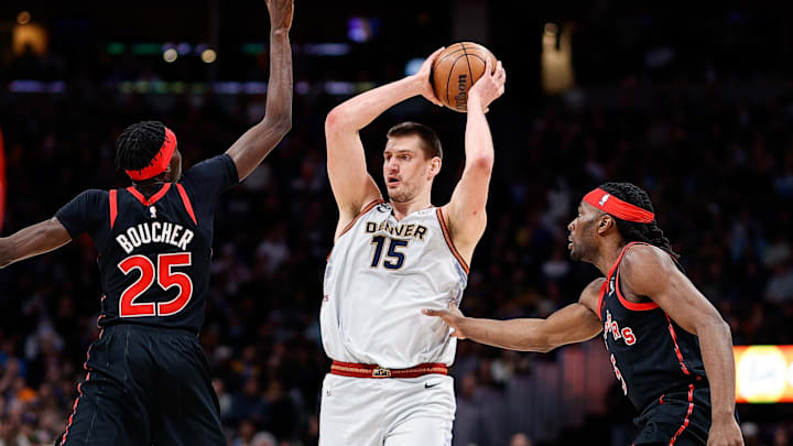 Mar 6, 2023; Denver, Colorado, USA; Denver Nuggets center Nikola Jokic (15) controls the ball against Toronto Raptors forward Chris Boucher (25) and forward Precious Achiuwa (5) in the first quarter at Ball Arena.