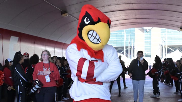 Oct 19, 2024; Louisville, Kentucky, USA; The Louisville Cardinals mascot greets fans during the Card March before facing off against the Miami Hurricanes at L&N Federal Credit Union Stadium. Oct 19, 2024; Louisville, Kentucky, USA; The Louisville Cardinals mascot greets fans during the Card March before facing off against the Miami Hurricanes at L&N Federal Credit Union Stadium.