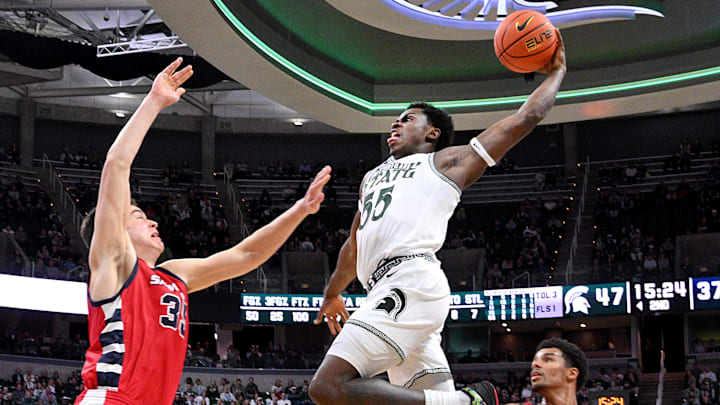 Nov 19, 2024; East Lansing, Michigan, USA;  Michigan State Spartans forward Coen Carr (55) leaps over Samford Bulldogs center Riley Allenspach (35) during the second half for a dunk at Jack Breslin Student Events Center. Mandatory Credit: Dale Young-Imagn Images