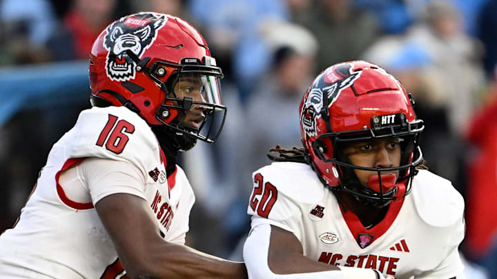 Nov 30, 2024; Chapel Hill, North Carolina, USA; North Carolina State Wolfpack quarterback CJ Bailey (16) hands the ball off to running back Hollywood Smothers (20) the ball in the first quarter at Kenan Memorial Stadium. Mandatory Credit: Bob Donnan-Imagn Images