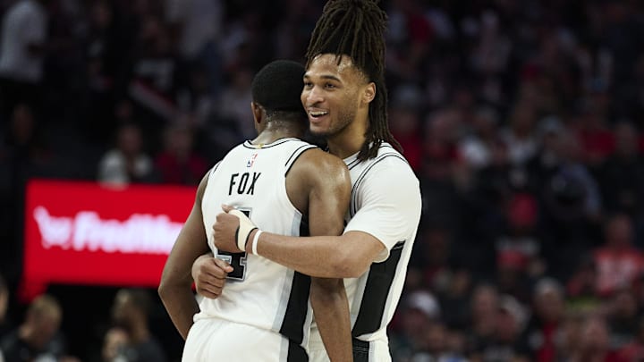 Apr 26, 2026; Portland, Oregon, USA; San Antonio Spurs guard Stephon Castle (5) embraces guard De'aaron Fox (4) during the second half in a game against the Portland Trail Blazers during game four of the first round of the 2026 NBA Playoffs at Moda Center. Mandatory Credit: Troy Wayrynen-Imagn Images
