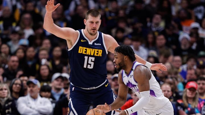 Dec 22, 2025; Denver, Colorado, USA; Utah Jazz guard Isaiah Collier (8) controls the ball against Denver Nuggets center Nikola Jokic (15) as guard Peyton Watson (8) defends in the third quarter at Ball Arena. Mandatory Credit: Isaiah J. Downing-Imagn Images