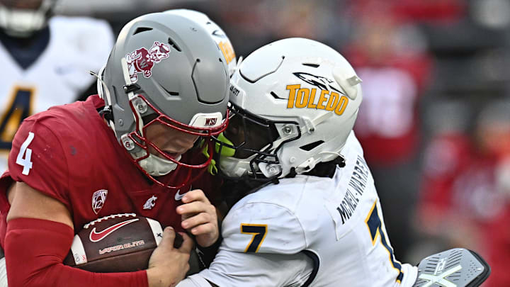 Oct 25, 2025; Pullman, Washington, USA; Washington State Cougars quarterback Zevi Eckhaus (4) is tackled by Toledo Rockets safety Emmanuel McNeil-Warren (7) in the second half at Gesa Field at Martin Stadium. Mandatory Credit: James Snook-Imagn Images