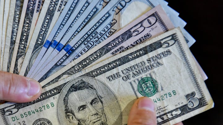 In this photo illustration, a person is seen holding 100, 50...