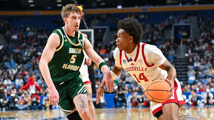 Mar 19, 2026; Buffalo, NY, USA; Louisville Cardinals guard Adrian Wooley (14) dribbles and looks to pass as South Florida Bulls guard Joseph Pinion (5) defends during the first half during a first round game of the men's 2026 NCAA Tournament at Keybank Center. Mandatory Credit: Mark Konezny-Imagn Images