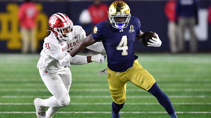 Dec 20, 2024; Notre Dame, Indiana, USA; Notre Dame Fighting Irish running back Jeremiyah Love (4) runs against Indiana Hoosiers linebacker Rolijah Hardy (21) during the third quarter at Notre Dame Stadium. Mandatory Credit: Matt Cashore-Imagn Images