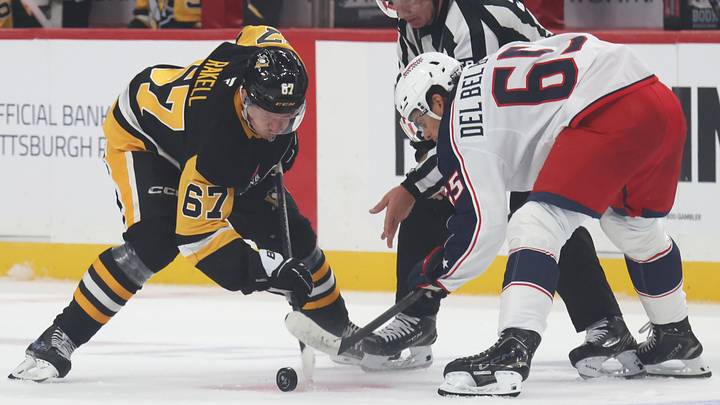 Blue Jackets center Luca Del Bel Belluz takes a faceoff against Penguins wing Rickard Rakell