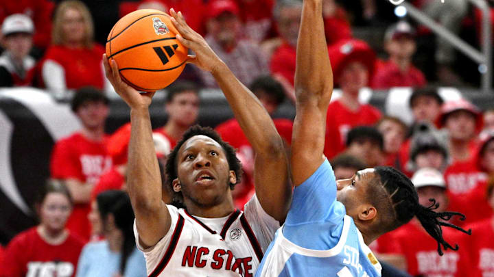 Feb 17, 2026; Raleigh, North Carolina, USA;  NC State Wolfpack guard Quadir Copeland (11) lays the ball up against North Carolina Tar Heels forward Jarin Stevenson (15) during the first half at Lenovo Center. Mandatory Credit: Zachary Taft-Imagn Images