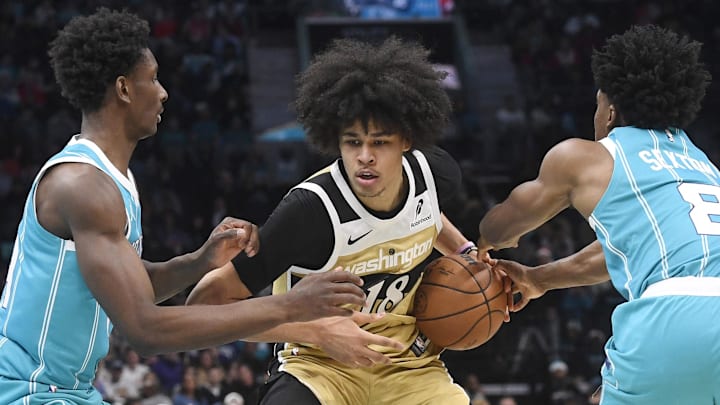 Dec 23, 2025; Charlotte, North Carolina, USA;  Washington Wizards guard Kyshawn George (18) drives past Charlotte Hornets forward Moussa Diabate (14) and guard Collin Sexton (8) during the first half at the Spectrum Center. Mandatory Credit: Sam Sharpe-Imagn Images