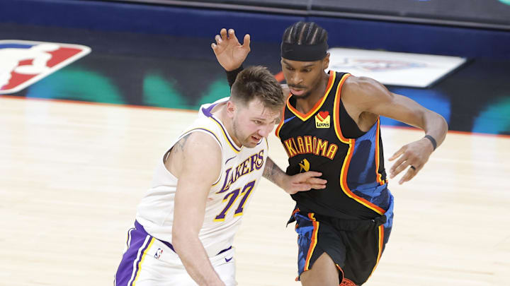 Apr 6, 2025; Oklahoma City, Oklahoma, USA; Los Angeles Lakers guard Luka Doncic (77) drives down the court beside Oklahoma City Thunder guard Shai Gilgeous-Alexander (2) during the second half at Paycom Center. Mandatory Credit: Alonzo Adams-Imagn Images