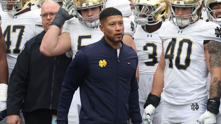 Nov 15, 2025; Pittsburgh, Pennsylvania, USA;  Notre Dame Fighting Irish head coach Marcus Freeman (middle) leads the team onto the field to play the Pittsburgh Panthers at Acrisure Stadium. 