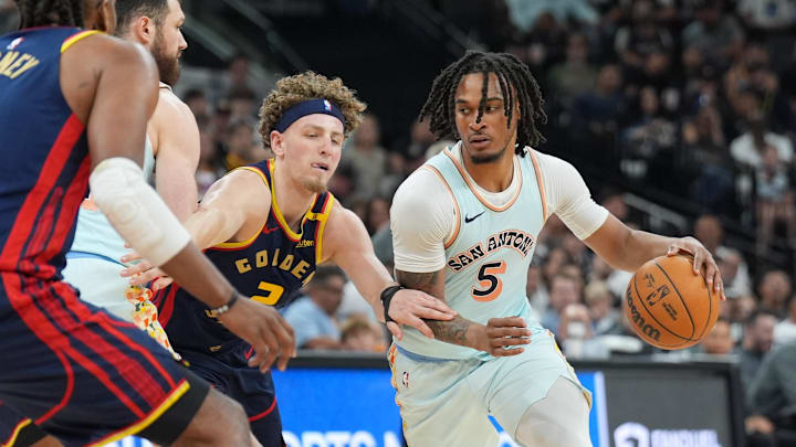 Mar 30, 2025; San Antonio, Texas, USA; San Antonio Spurs guard Stephon Castle (5) dribbles past Golden State Warriors guard Brandin Podziemski (2) in the second half at Frost Bank Center.