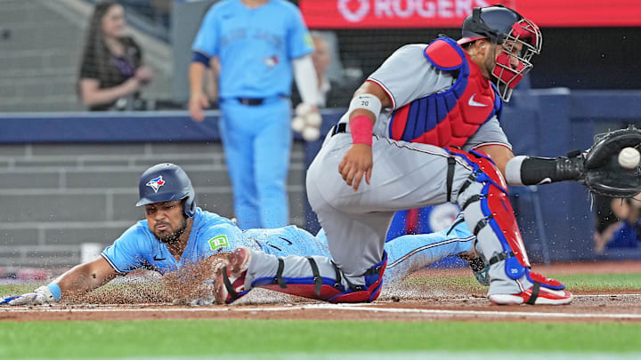 Apr 2, 2025; Toronto, Ontario, CAN; Toronto Blue Jays right fielder Anthony Santander (25) slides into home scoring a run ahead of the tag from Washington Nationals catcher Keibert Ruiz (20) during the first inning at Rogers Centre. Mandatory Credit: Nick Turchiaro-Imagn Images