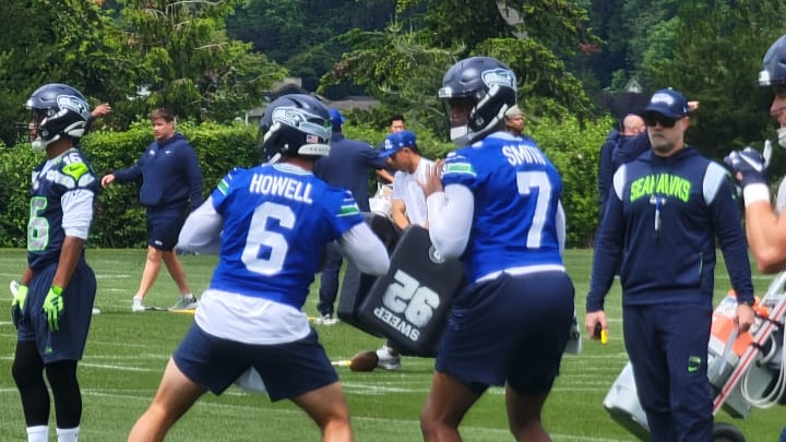 Seahawks offensive coordinator Ryan Grubb watches as quarterbacks Geno Smith and Sam Howell prepare to throw during a team drill at OTAs.