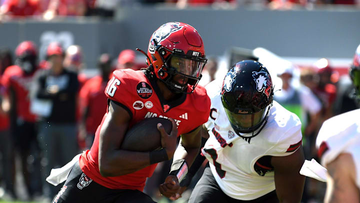 Sep 28, 2024; Raleigh, North Carolina, USA; North Carolina State Wolfpack quarter back CJ Bailey (16) runs the ball for a touchdown against the Northern Illinois Huskies in the first quarter at Carter-Finley Stadium. Mandatory Credit: Zachary Taft-Imagn Images