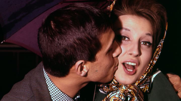 A man kisses a woman holding an umbrella at the Sanremo Music Festival 