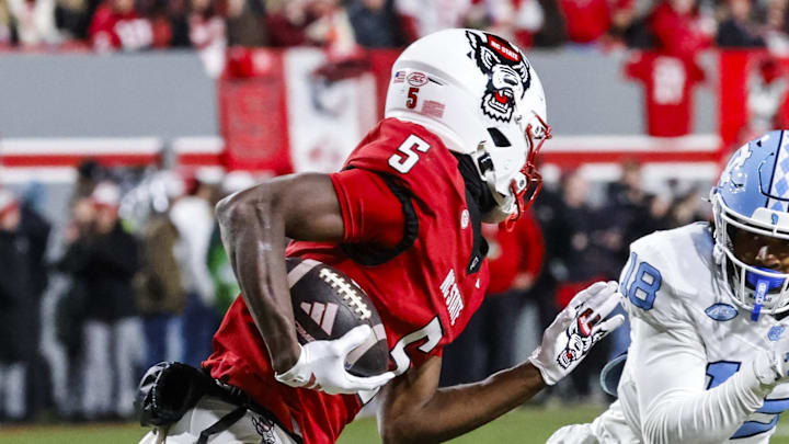 Nov 29, 2025; Raleigh, North Carolina, USA;  NC State Wolfpack wide receiver Noah Rogers (5) runs with the ball guarded by North Carolina Tar Heels defensive back Jaiden Patterson (18) during the first half of the game at Carter-Finley Stadium.  Mandatory Credit: Jaylynn Nash-Imagn Images
