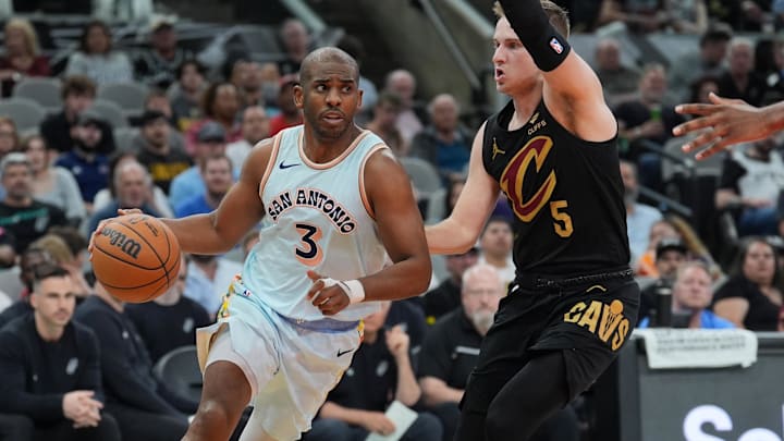 Apr 4, 2025; San Antonio, Texas, USA;  San Antonio Spurs guard Chris Paul (3) dribbles against Cleveland Cavaliers guard Sam Merrill (5) in the second half at Frost Bank Center. Mandatory Credit: Daniel Dunn-Imagn Images