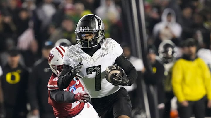 Nov 16, 2024; Madison, Wisconsin, USA;  Oregon Ducks wide receiver Evan Stewart (7) rushes with the football in front of Wisconsin Badgers cornerback Ricardo Hallman (2) after catching a pass during the fourth quarter at Camp Randall Stadium. Mandatory Credit: Jeff Hanisch-Imagn Images