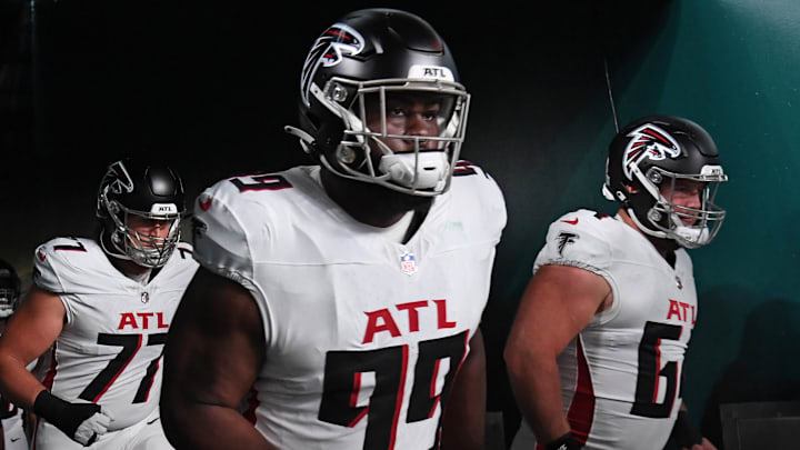 Former Atlanta Falcons defensive tackle Eddie Goldman (99) and guard Ryan Neuzil (64) run onto the field against the Philadelphia Eagles for a 2024 NFL contest at Lincoln Financial Field. Goldman recently signed with his hometown Washington Commanders.