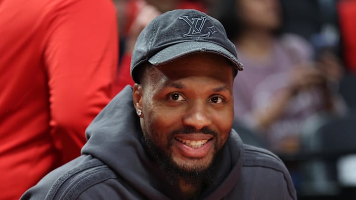 Oct 10, 2025; Portland, Oregon, USA;  Portland Trail Blazers guard Damian Lillard  (0) smiles while sitting on the bench before the Trail Blazers plays Sacramento Kings at Moda Center. Mandatory Credit: Jaime Valdez-Imagn Images