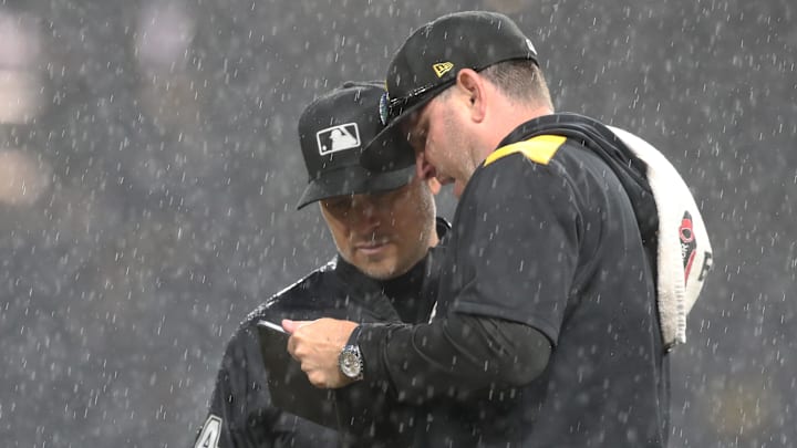 May 22, 2025; Pittsburgh, Pennsylvania, USA;  Pittsburgh Pirates grounds crew chief Mattt Brown (right) talks with MLB umpire crew chief Mark Wegner (14) as a heavy rain delays the game against the Milwaukee Brewers in the sixth inning at PNC Park. Mandatory Credit: Charles LeClaire-Imagn Images