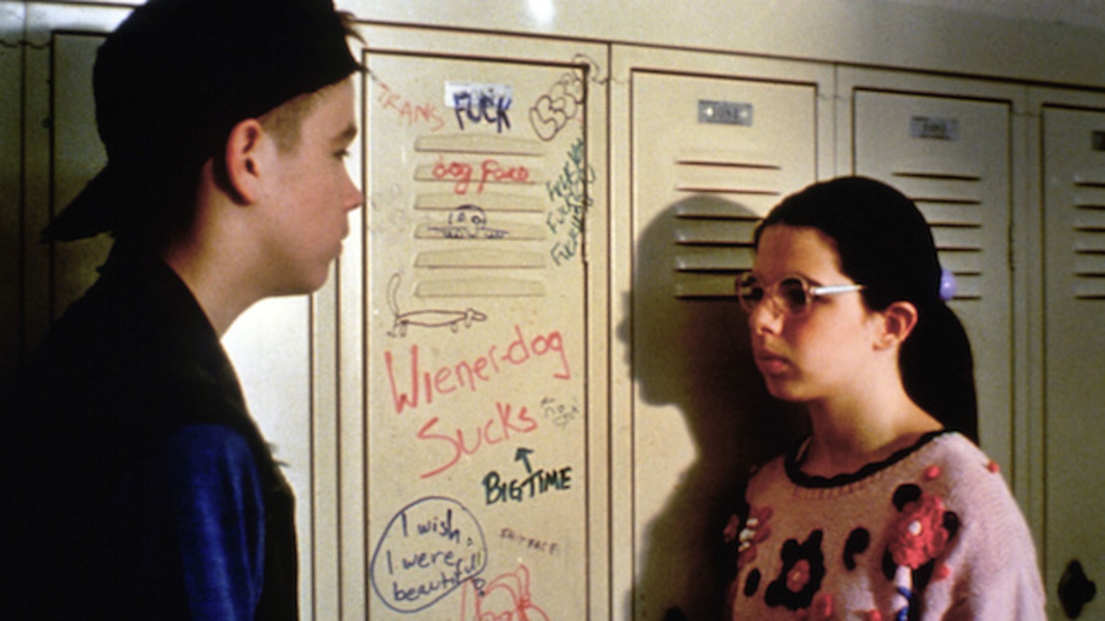 Brand & Dawn talk in front of her locker at school which is vandalized with graffiti that says Weiner-Dog Sucks in Welcome to the Dollhouse.