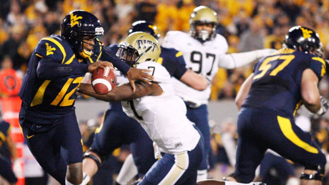 MORGANTOWN, WV - NOVEMBER 25: Geno Smith #12 of the West Virginia Mountaineers evades a tackle from Brandon Lindsey #7 of the University of Pittsburgh Panthers during the 2011 Backyard Brawl on November 25, 2011 at Mountaineer Field in Morgantown, West Virginia. (Photo by Jared Wickerham/Getty Images)