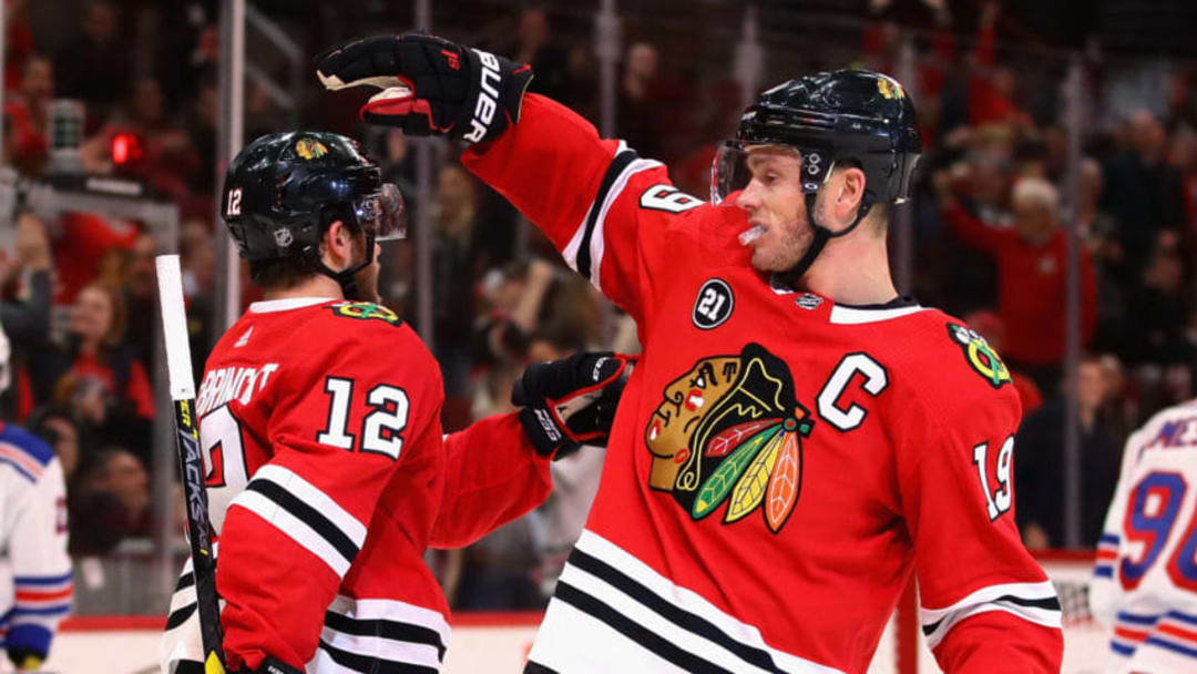 CHICAGO, IL - OCTOBER 25: Alex DeBrincat #12 of the Chicago Blackhawks gets a pat on the head from Jonathan Toews #19 after scoring an empty net goal in the third period against the New York Rangers at the United Center on October 25, 2018 in Chicago, Illinois. The Blackhawks defeated the Rangers 4-1. (Photo by Jonathan Daniel/Getty Images)