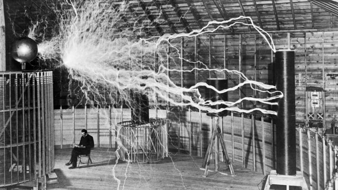 Nikola Tesla demonstrates alternating current (AC) in his lab in 1901.