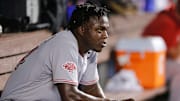 Arístides Aquino observa en el dogout durante un partido de MLB entre Rojos y Marlins