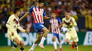 Oribe Peralta controla un balón ante la marca de dos jugadores del América.