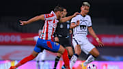 Jugadores de Chivas y de Pumas UNAM pelean un balón.