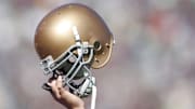 A Notre Dame helmet held in the air symbolically. 