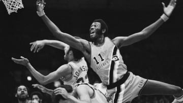 (Original Caption) Buffalo's Bob McAdoo, (11) goes over Cavalier's Lenny Wilkens (19 and bending over) and John Johnson (32) to score a basket during half play here on November 3rd. The Cavaliers won their third straight game, dumping the Braves 124-97.