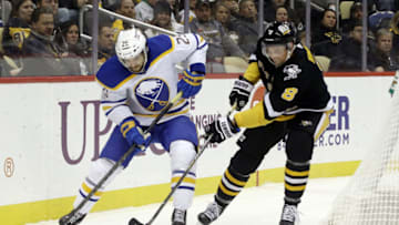 Dec 17, 2021; Pittsburgh, Pennsylvania, USA; Buffalo Sabres center Vinnie Hinostroza (29) and Pittsburgh Penguins defenseman Brian Dumoulin (8) chase the puck during the third period at PPG Paints Arena. The Penguins won 3-2 in overtime. Mandatory Credit: Charles LeClaire-USA TODAY Sports
