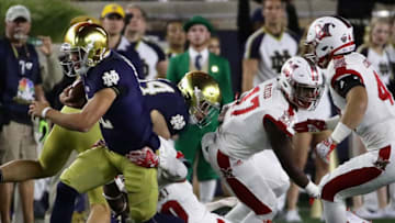 SOUTH BEND, IN - SEPTEMBER 30: Ian Book #12 of the Notre Dame Fighting Irish is tackled by Josh Maize #30 of the Miami (Oh) Redhawks at Notre Dame Stadium on Seotember 30, 2017 in South Bend, Indiana. (Photo by Jonathan Daniel/Getty Images)