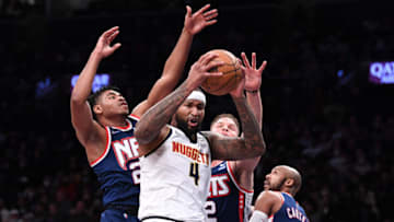 Jan 26, 2022; Brooklyn, New York, USA; Denver Nuggets Center DeMarcus Cousins (4) reaches for the ball while defended by Brooklyn Nets forward Blake Griffin (2) and guard Cam Thomas (24) during the second quarter at Barclays Center. Mandatory Credit: Dennis Schneidler-USA TODAY Sports