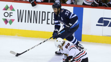WINNIPEG, MANITOBA - APRIL 7: Dustin Byfuglien #33 of the Winnipeg Jets moves the puck past Patrick Kane #88 of the Chicago Blackhawks during NHL action on April 7, 2018 at Bell MTS Place in Winnipeg, Manitoba. (Photo by Jason Halstead /Getty Images)